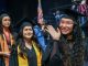 Hispanic female graduates in caps and gowns smile and wave during a graduation ceremony. The Tu Camino Scholarship supports Hispanic adults pursuing career growth through education. Credit: Lone Star College System.